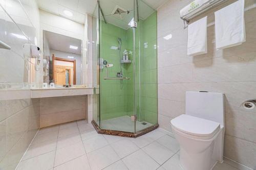 a bathroom with a toilet and a glass shower at GreenTree Inn Haixi Geermu Southern suburbs Express Hotel in Golmud