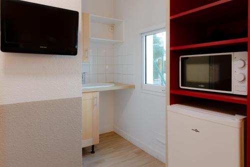 a small kitchen with a microwave and a window at Première Classe Plaisir Gatines in Plaisir