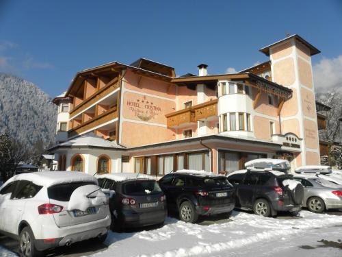 a large building with cars parked in the snow at Hotel Cristina in Pinzolo
