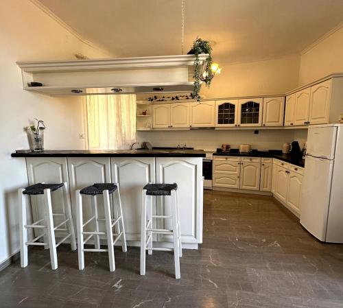 a kitchen with white cabinets and bar stools at Lyra House in Mikro Metochi