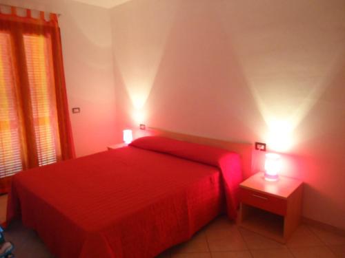 カステルサルドにあるAppartamento Incanto Castelsardo Sardegnaのベッドルーム1室(赤いベッド1台、ナイトスタンド2台付)