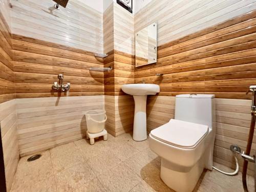 a bathroom with a toilet and a wooden wall at Hotel Pacific Paradise, Lavish & Luxury Stay In Haridwar in Haridwār