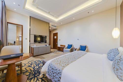 a bedroom with a large bed and a living room at YUN-RAY Hotel Shijiazhuang in Shijiazhuang