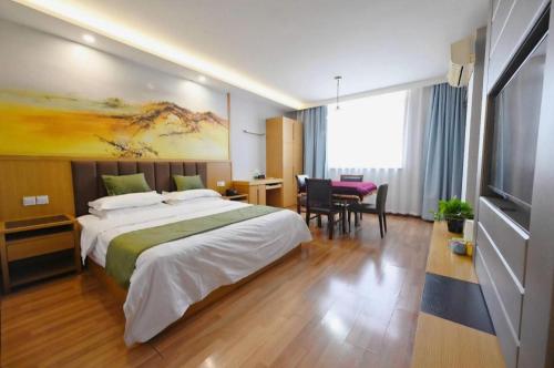 a hotel room with a large bed and a table at GreenTree Inn Gaoyou Government in Yangzhou