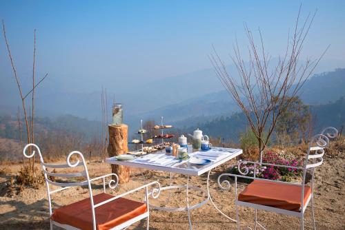 a table and chairs sitting on top of a mountain at The Orchard at Peora Estates in Mukteswar