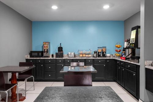 a large kitchen with black cabinets and a blue wall at Days Inn by Wyndham Phoenix West in Phoenix