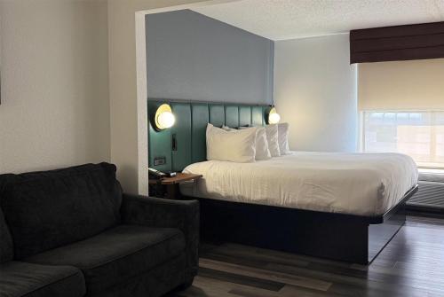 a bedroom with a bed and a couch and a chair at Wingate by Wyndham Airport - Rockville Road in Indianapolis