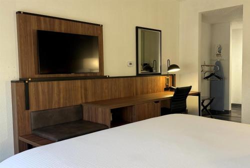 a bedroom with a desk with a television and a bed at Wingate by Wyndham Airport - Rockville Road in Indianapolis