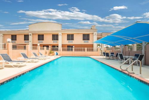 マッカレンにあるDays Inn by Wyndham McAllenの椅子と建物のあるプール