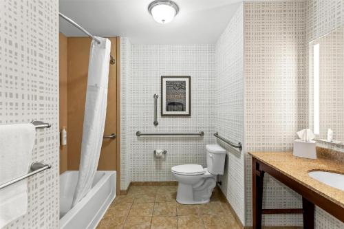 a bathroom with a toilet and a tub and a sink at Hampton Inn Dekalb - Near the University in DeKalb
