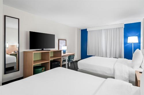 a hotel room with two beds and a flat screen tv at Spark by Hilton Orlando near Universal in Orlando