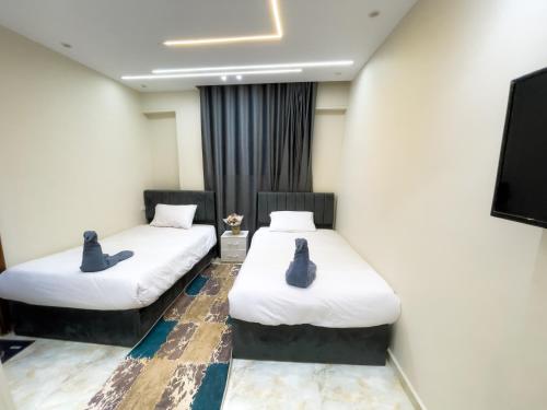 two beds in a room with a tv at Kemet Pyramids INN in Cairo