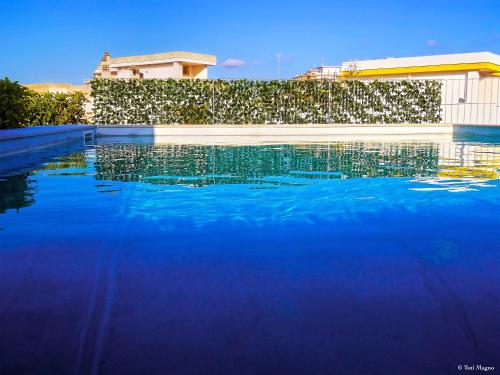 - une piscine d'eau bleue en face d'un bâtiment dans l'établissement Felicity Residence, à Gallipoli