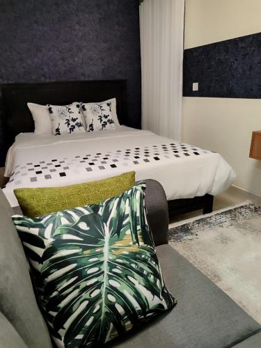 a bedroom with a bed and a couch with a pillow at Swanky Stays Studio Ngong in Nairobi