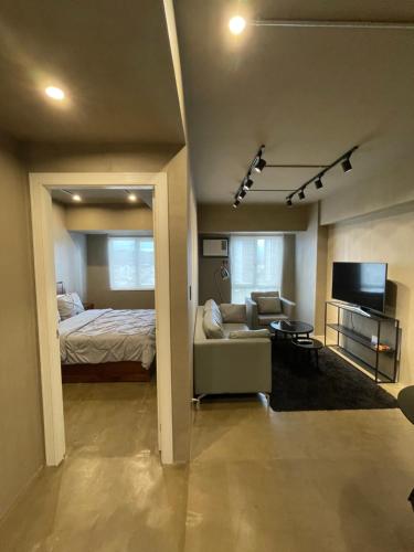 a room with a bed and a couch and a television at 1-BR Luxury Condo, Centrio Tower, Ayala Malls in Cagayan de Oro