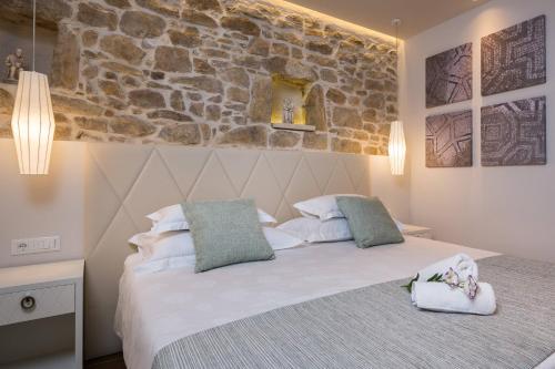 Un dormitorio con una cama con una pared de piedra. en Balatura The Fine Bed&Breakfast Split, en Split