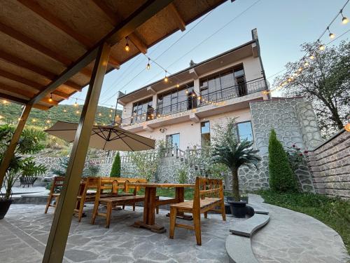 a patio with a wooden table and chairs and a house at TIGRAN Hotel by Black & Gold in Goris