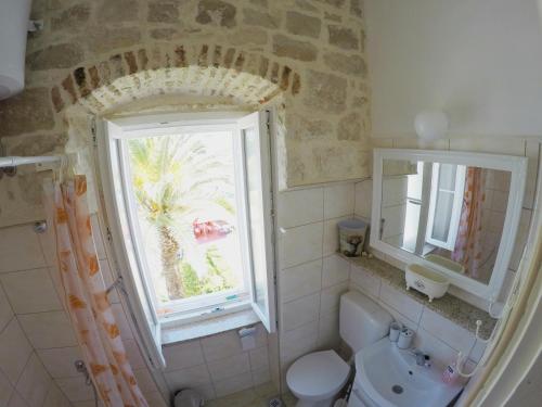a bathroom with a window and a toilet and a sink at Castel Nonna Franka in Sutivan