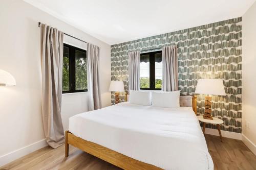 a bedroom with a large white bed and two windows at Roami at The Palace in Miami