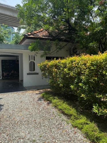 a white house with a hedge in front of it at Cozy nature homestay in Kuala Lumpur