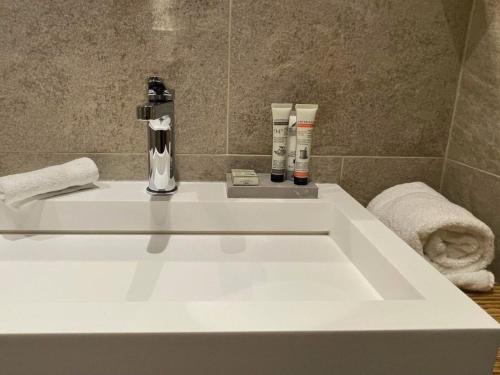a white bathroom sink with two products on it at Boutique Hotel Art de Vivre & SPA in Crans-Montana