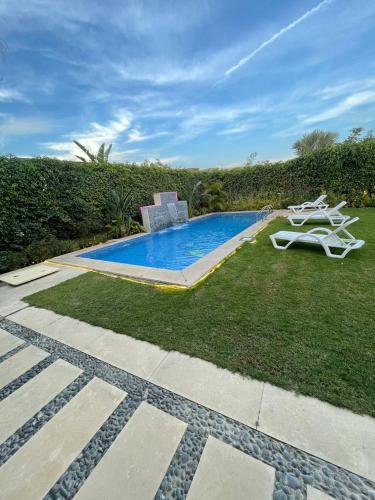 ein Pool in einem Garten neben einem Rasenplatz in der Unterkunft فيلا مع حمام سباحه وجاردن 0306-888-0106 in Kairo