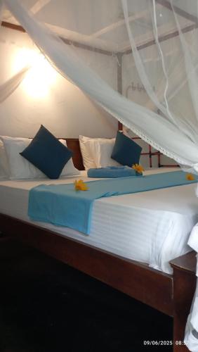 a bed with blue and white sheets and pillows at Quiet Place villa with kitchen in Tangalle