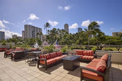 eine Terrasse mit Sofas, Tischen und Stühlen in der Unterkunft DoubleTree by Hilton Alana - Waikiki Beach in Honolulu