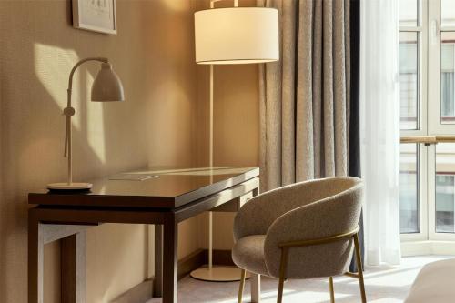 a desk in a room with a lamp and a chair at Hilton Vienna Plaza in Vienna