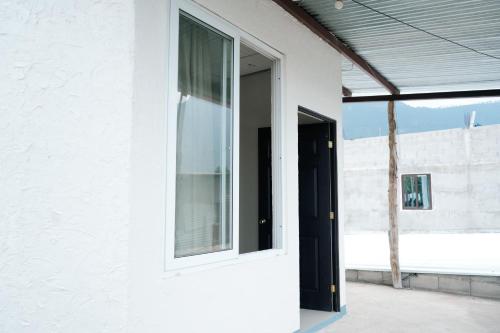a white house with a window and a door at Hostal Casa Ale in San Juan La Laguna