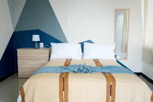 a bedroom with a large bed with a blue accent at Hostal Casa Ale in San Juan La Laguna