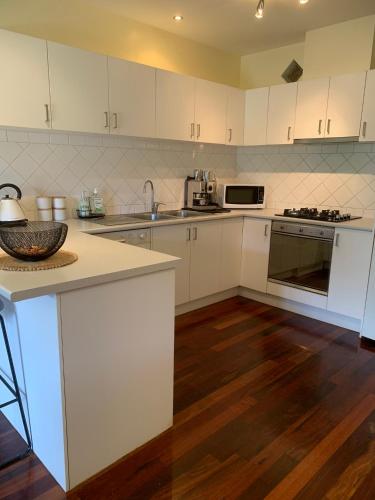 a kitchen with white cabinets and a wooden floor at Halls Gap Escape Townhouses in Halls Gap