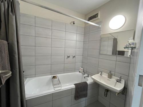 a white bathroom with a tub and a sink at Keith's Condo in Cape Town