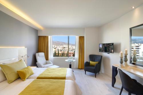 アテネにあるAthens Avenue Hotelのベッドとデスクが備わるホテルルームです。