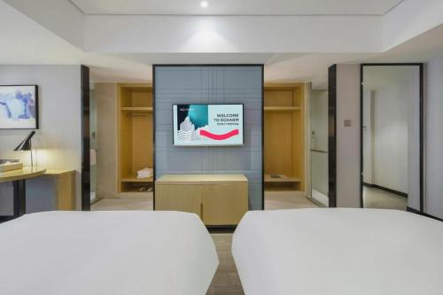 a room with two beds and a tv on a wall at Echarm Hotel Beihai Railway Station in Beihai