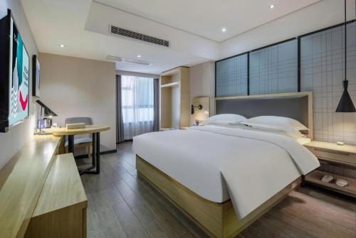 a bedroom with a large white bed and a desk at Echarm Hotel Beihai Railway Station in Beihai