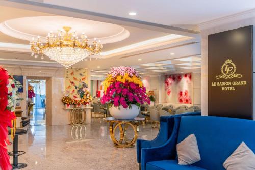 a lobby with a large vase of flowers and a chandelier at Le Saigon Grand Hotel in Ho Chi Minh City