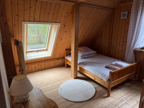 a bedroom with a bed in a cabin with a window at Leśna Chata Arciechów in Arciechow