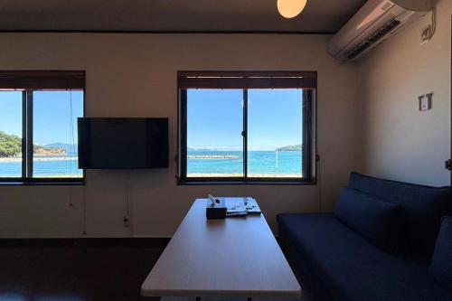 a living room with a couch and a table and windows at シーサイド興津 in Sanuki