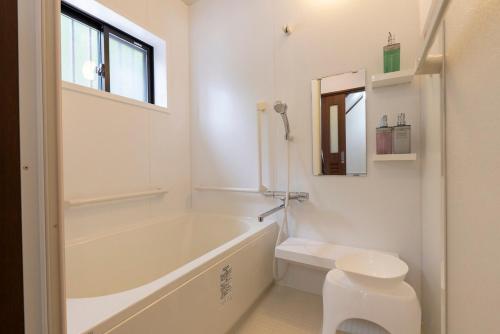 a bathroom with a tub and a toilet and a sink at シーサイド興津 in Sanuki