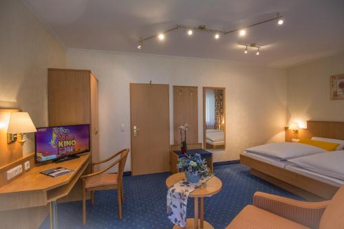 a hotel room with a bed and a desk and a television at Gasthof Rodachtal mit Gästehaus Katharina in Schwarzenbach am Wald