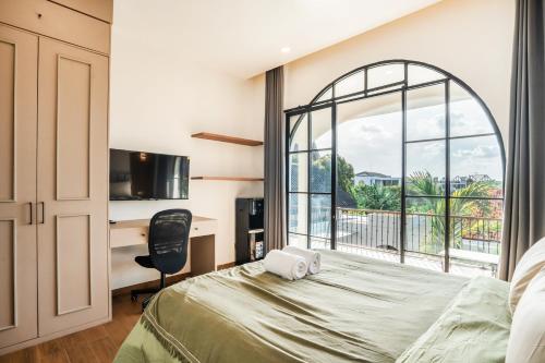 une chambre avec un lit, un bureau et une fenêtre dans l'établissement Le Jardin CoLiving A2 - Upscale Apt, Canggu center, à Canggu