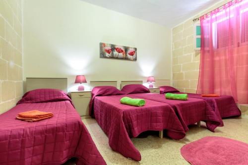 two beds in a room with pink sheets at Serenity - Bellevue Gozo in Xlendi