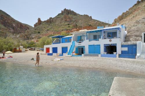 a woman standing on a beach next to a house at Erginas Boat House in Plaka Milou