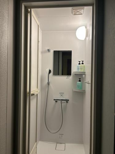 a bathroom with a shower with a sink and a mirror at Yoroi Asakusa Hotel in Tokyo