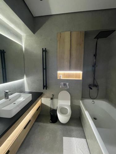 een badkamer met een wastafel, een toilet en een bad bij 13 mountains in Bisjkek