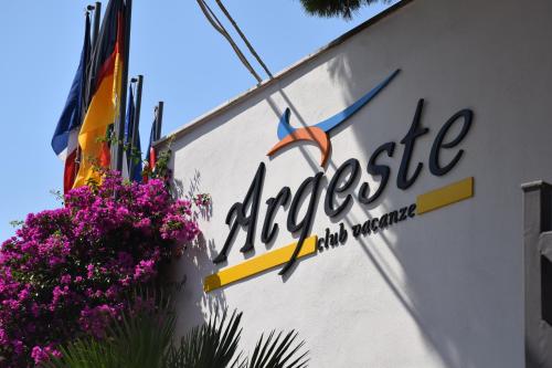 een winkelbord aan de zijkant van een gebouw met paarse bloemen bij Argeste Club Vacanze in Vieste