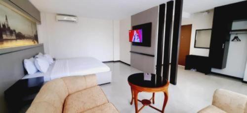 a living room with a bed and a couch and a tv at Alexander Hotel Tegal in Tegal
