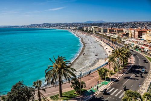 a view of a beach with palm trees and the ocean at Studio vue mer clim plage aéroport Nice centre commercial centre affaires Nice Arenas emplacement excellent in Saint-Laurent-du-Var