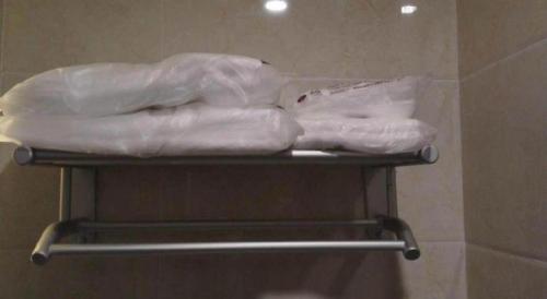 a towel rack with some white towels on it at 7 Days Premium Tangshan Railway Station Jiaotong University in Tangshan